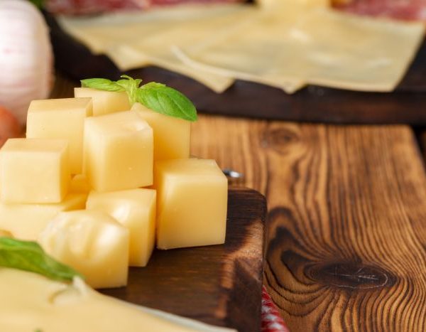 Wooden platter with cheese pieces and melted cheese