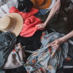 femeie care cauta in haine vechi intinse pe podea