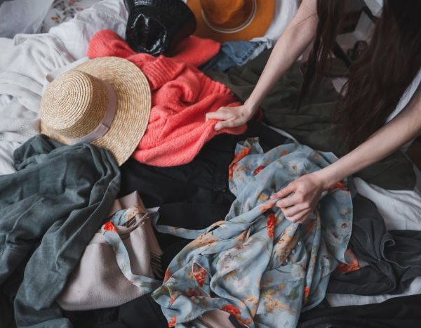 woman searching through old clothes lying on the floor