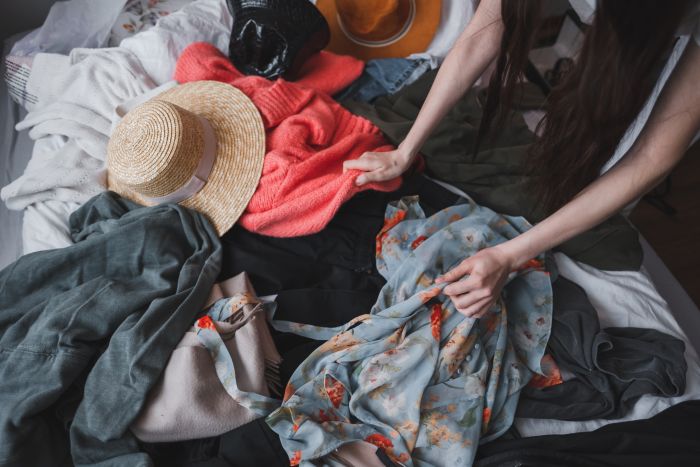 woman searching through old clothes lying on the floor