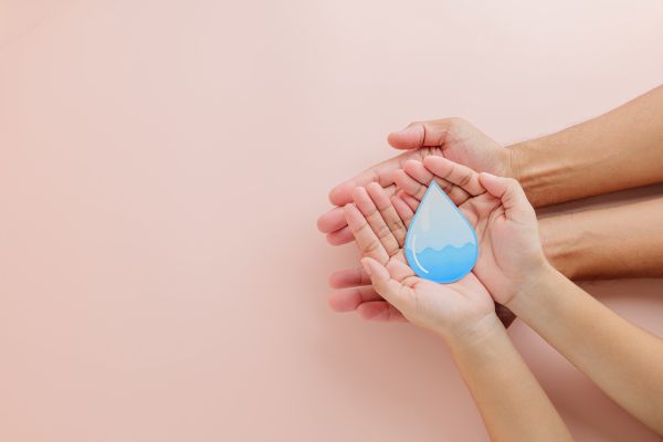 doua perechi de maini care tin o picatura de apa