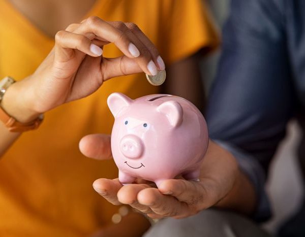woman putting money into piggy bank to save