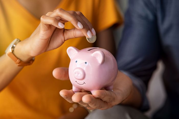woman putting money into piggy bank to save