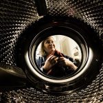 femeie care scoate rufe din cuva masinii de spalat rufe si se stramba din cauza mirosului neplacut