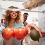 femeie care cauta in frigider alimente pentru a face mancare