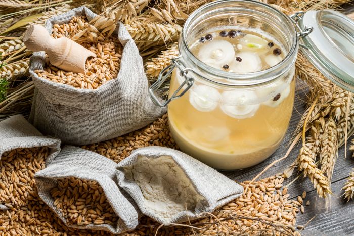 Boabe de grau pe o masa din lemn langa un borcan umplut cu bors